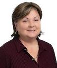 Headshot: Dark haired woman in black top smiling at the camera.